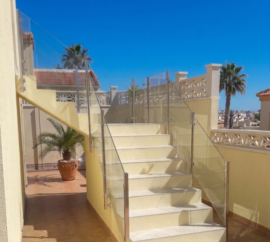 Transparent glass stair railing enhancing garden design in Rojales